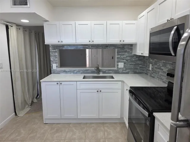 a kitchen with granite countertop a sink stove and refrigerator