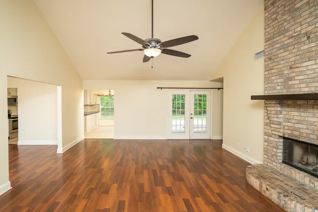 a view of empty room with wooden floor and fan