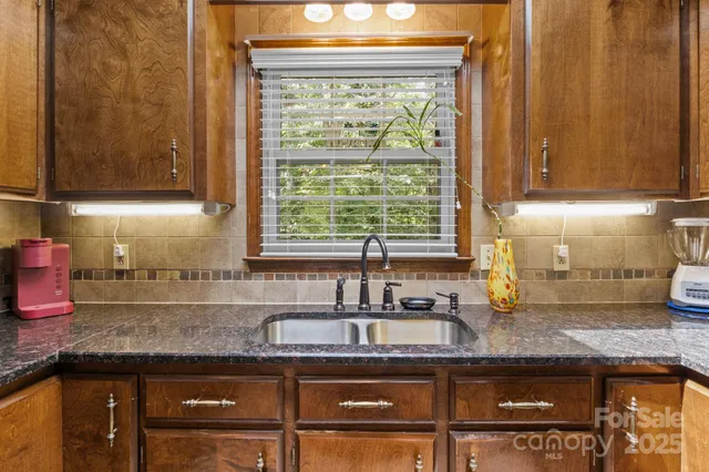 a kitchen with granite countertop a stove a sink and a microwave