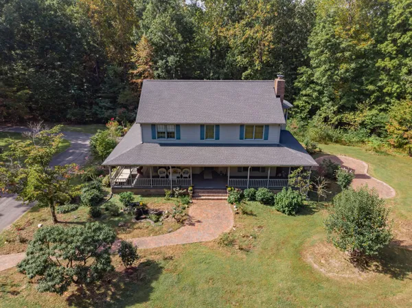 an aerial view of a house with outdoor space and trees all around