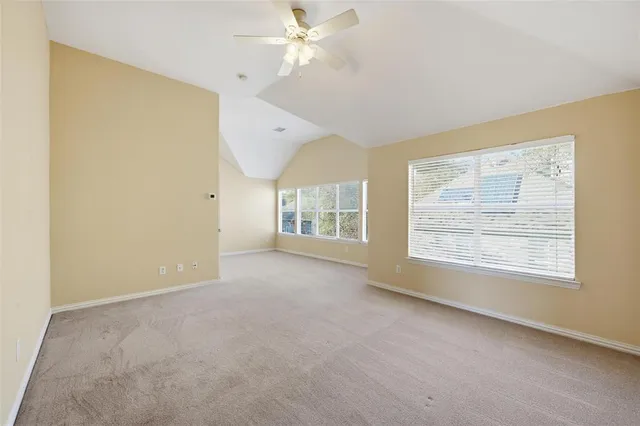 an empty room with chandelier fan and windows