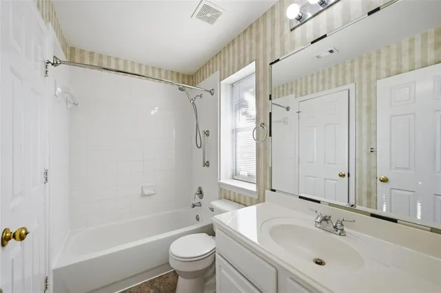 a bathroom with a bathtub shower sink mirror vanity and toilet