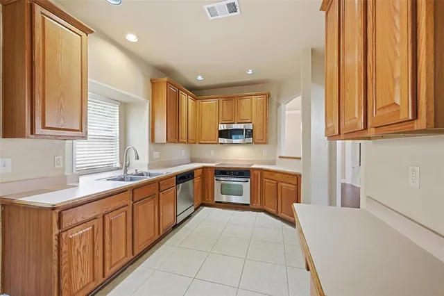 a large kitchen with stainless steel appliances granite countertop a sink and dishwasher a stove top oven with wooden floor