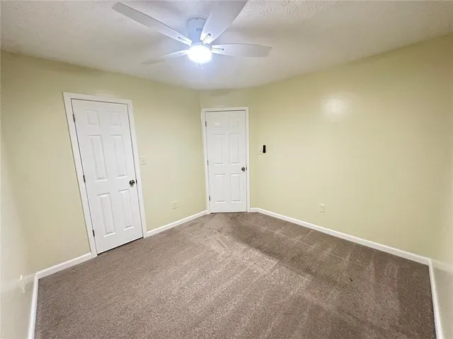 an empty room with a ceiling fan and a window