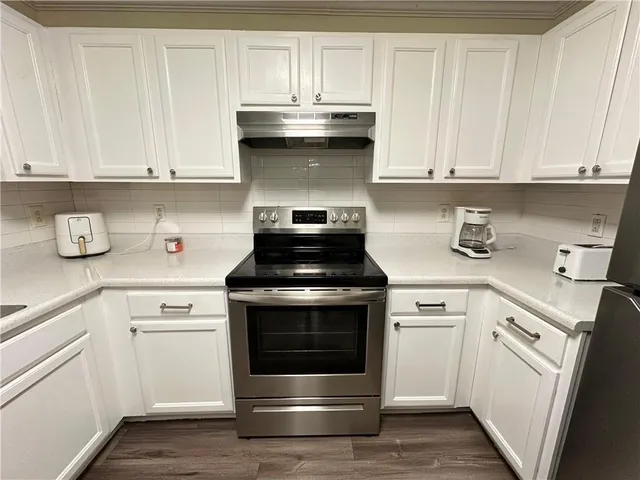 a kitchen with white cabinets and appliances