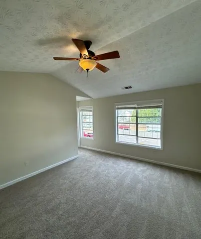 an empty room with windows and ceiling fan