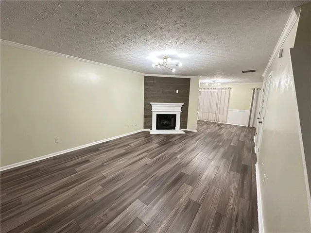 an empty room with wooden floor fireplace and windows