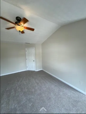 an empty room with a chandelier fan and a window