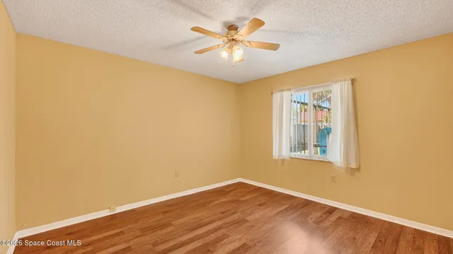 an empty room with wooden floor closet and windows