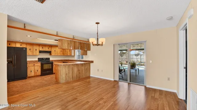 a view of a livingroom with a chandelier fan and wooden floor