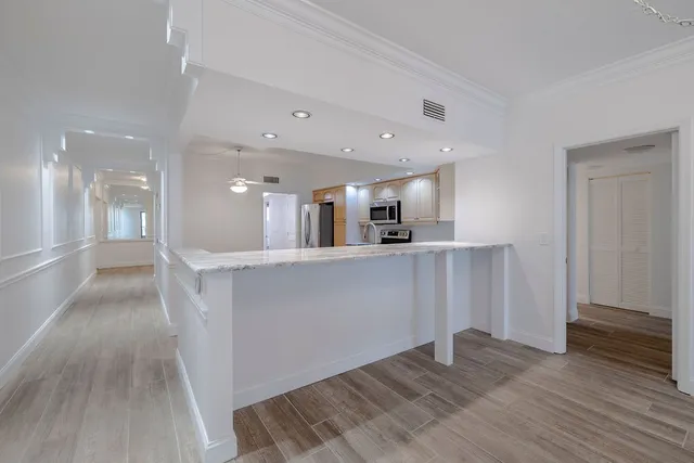 a view of a hallway with wooden floor and a kitchen