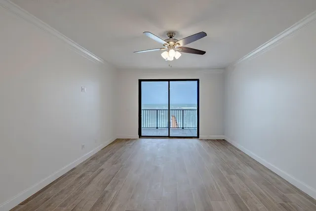 a view of an empty room with a window and wooden floor