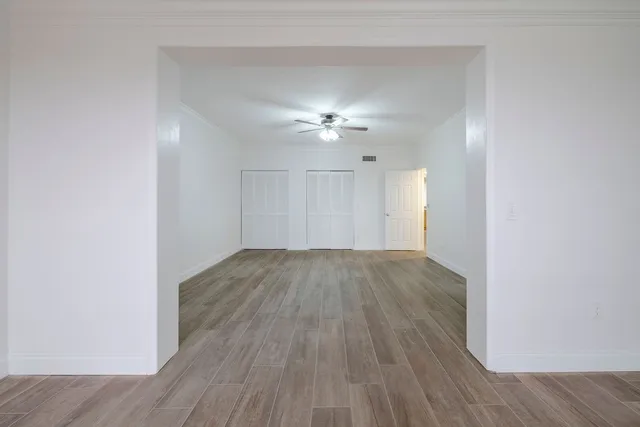 an empty room with wooden floor and a ceiling fan