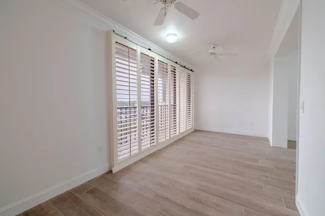 a view of an empty room with a window and wooden floor