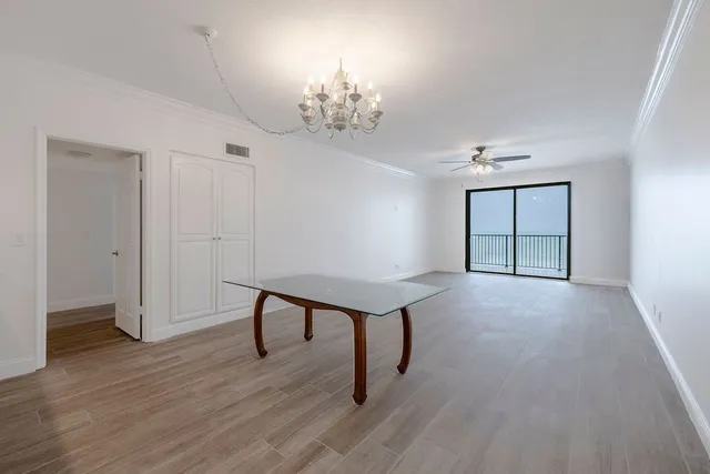 a view of a room with wooden floor chandelier and windows