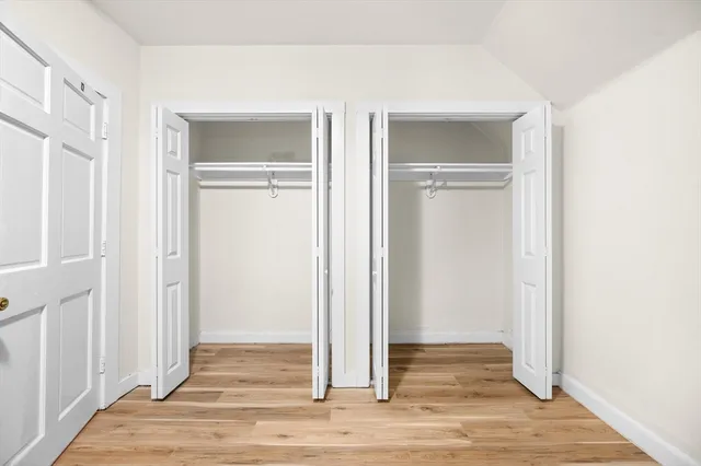 an empty room with wooden floor & closet area