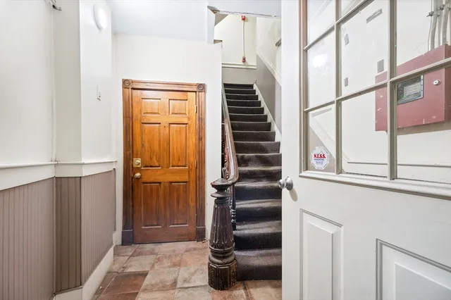 a view of staircase with lots of frames on wall and a window