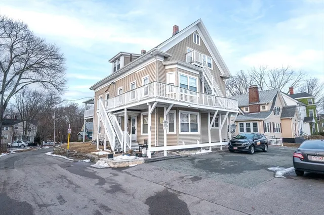 a front view of a building with lot of cars and trees