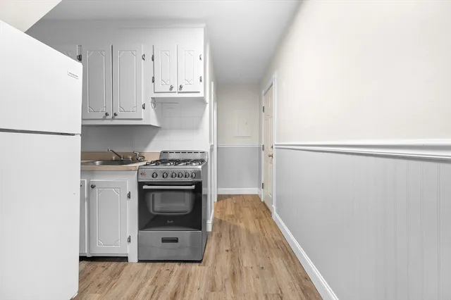 a kitchen with a white stove refrigerator and cabinets