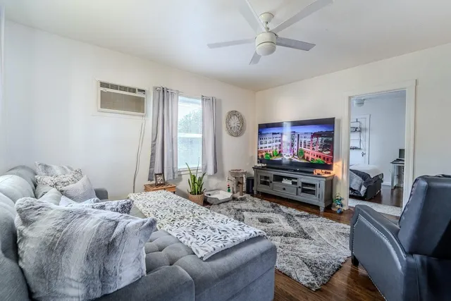 a living room with furniture a flat screen tv and a window