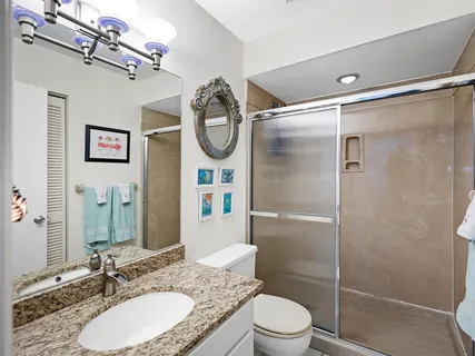 a bathroom with a granite countertop sink toilet a mirror and shower