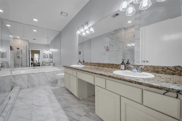 a large white kitchen with a large island oven a sink stainless steel appliances and chandelier