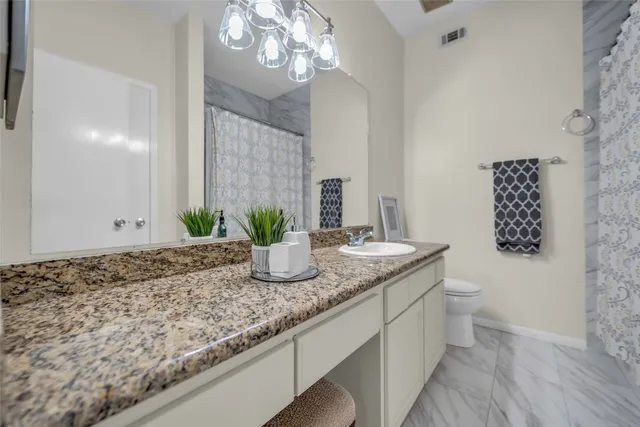 a bathroom with a granite countertop sink a toilet and with mirror