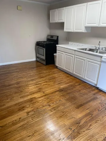 a kitchen with granite countertop a stove top oven a sink and white cabinets