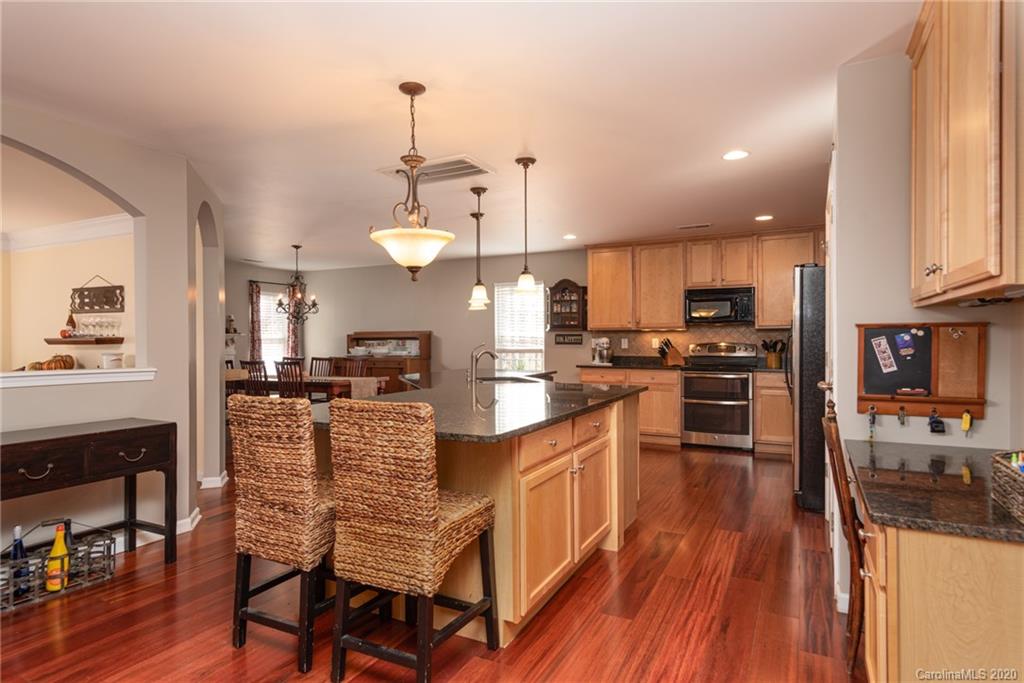 7838 East Berkeley Road Denver, NC 28037 - Photo 9 of 34 a kitchen with stainless steel appliances kitchen island granite countertop a refrigerator a stove top oven a sink dishwasher and wooden cabinets with wooden floor