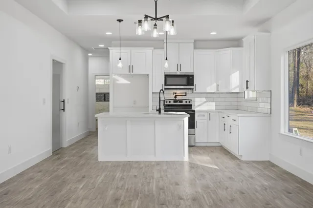a kitchen with stainless steel appliances a white stove top oven cabinets and a window