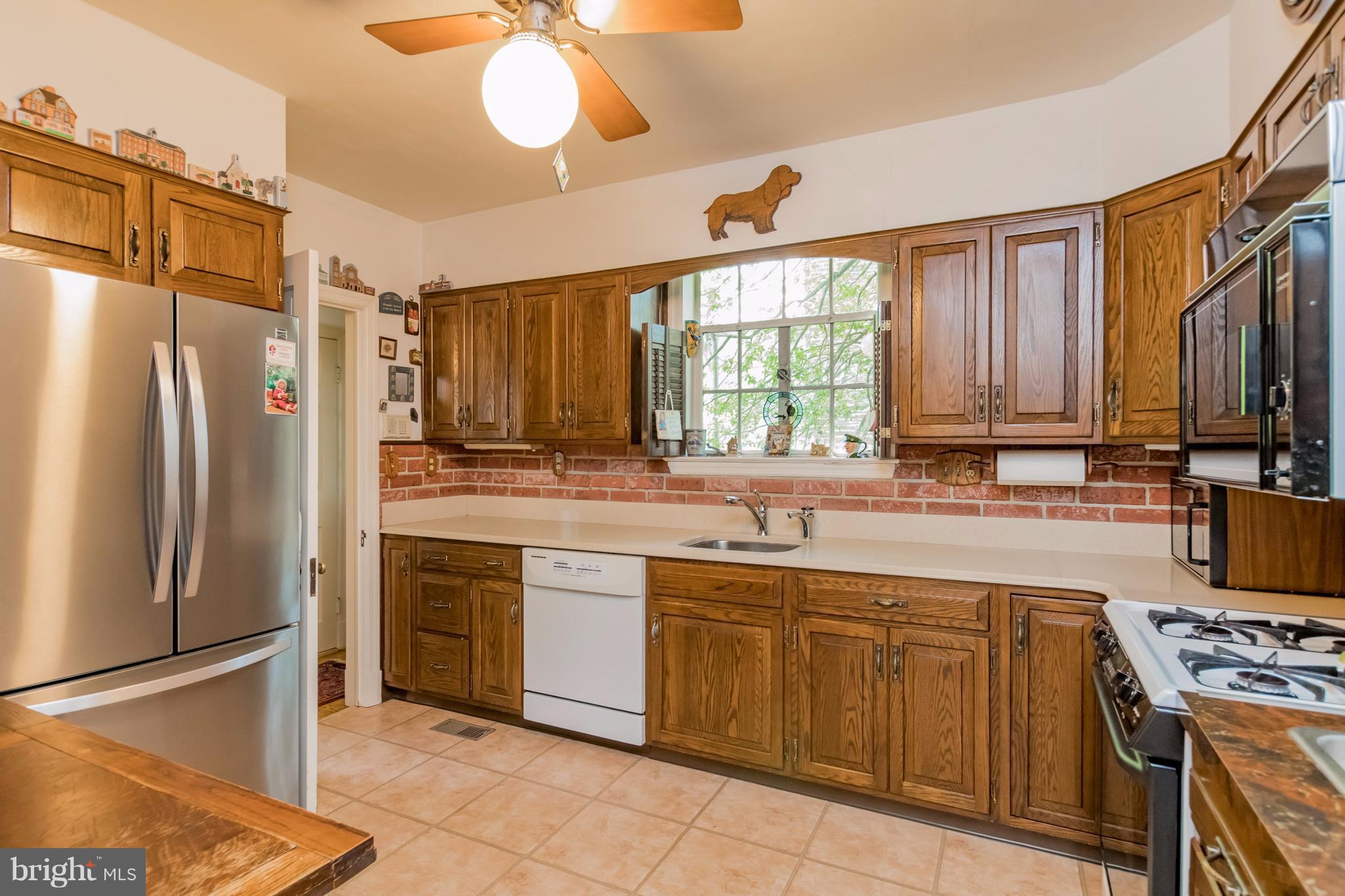 901 Kingston Road Baltimore, MD 21212 - Photo 9 of 27 a kitchen with stainless steel appliances granite countertop a refrigerator a sink dishwasher a stove and white countertops with wooden floor