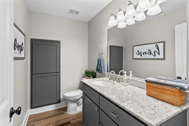 a bathroom with a granite countertop sink a toilet and a mirror