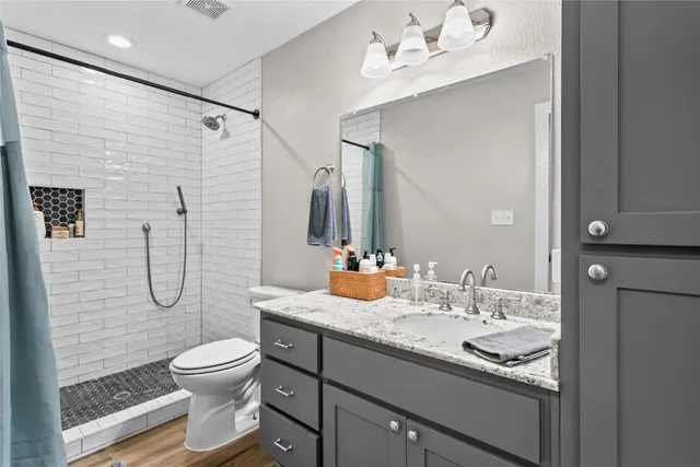 a bathroom with a granite countertop sink a toilet and shower