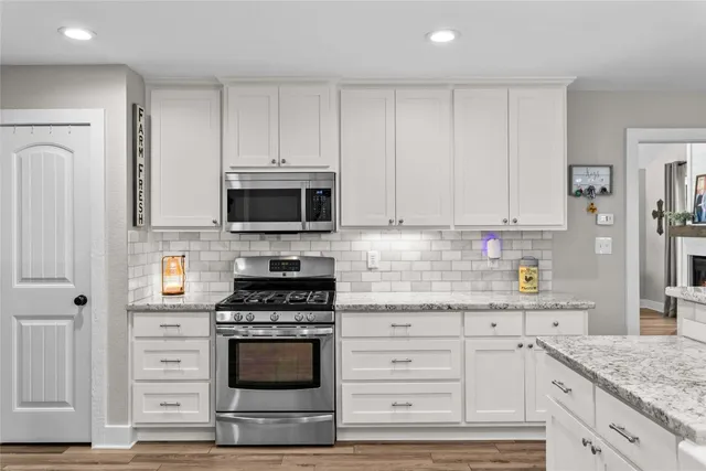 a kitchen with granite countertop white cabinets and stainless steel appliances
