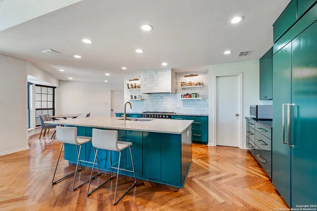 a kitchen with stainless steel appliances granite countertop a table chairs sink and cabinets
