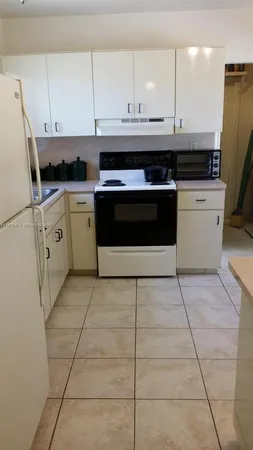 a kitchen with granite countertop a stove a sink and a refrigerator