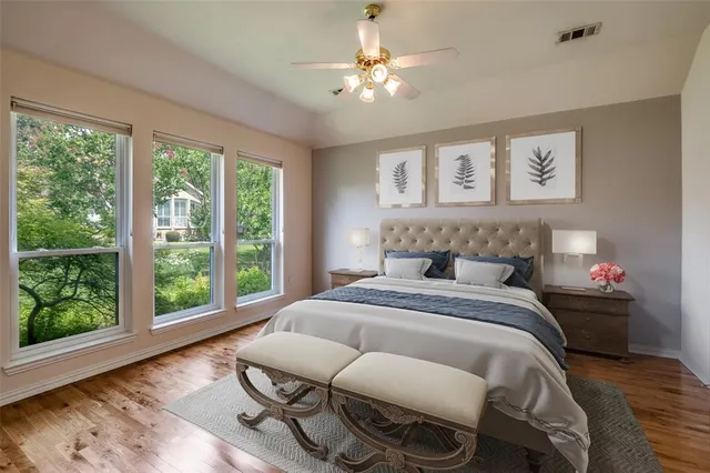 a view of an empty room with window a chandelier fan and wooden floor