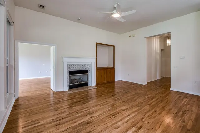 a view of an empty room with wooden floor and a fireplace