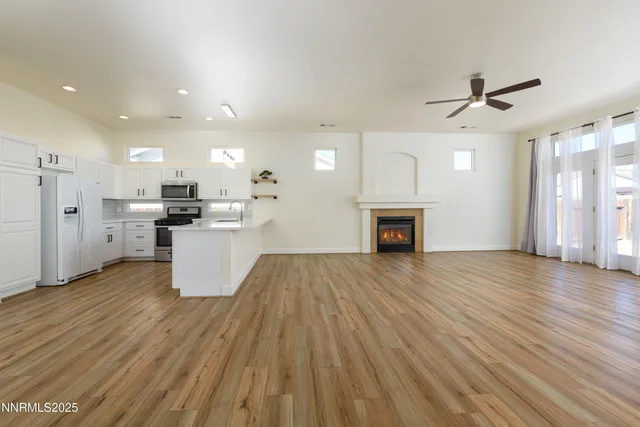 a view of empty room with wooden floor and kitchen