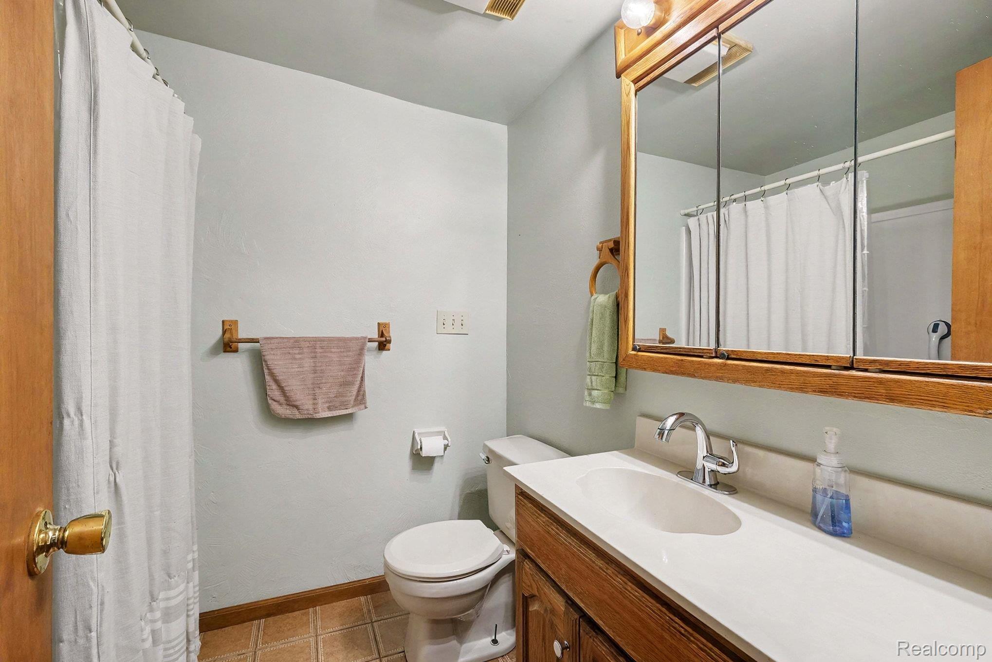 16059 Murray Road Byron, MI 48418 - Photo 19 of 32 Bathroom featuring a wood-finish vanity with an integrated sink, polished chrome faucet, and a large medicine cabinet with overhead lighting