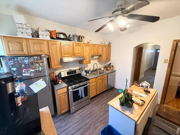 a kitchen with granite countertop a stove refrigerator and wooden floor