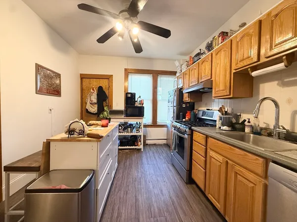 a kitchen with a stove a sink dishwasher and a stove with wooden floor