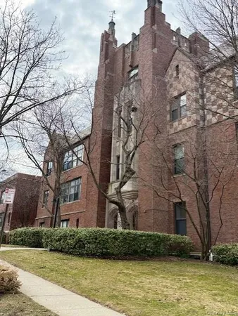a large brick building with a large tree in front