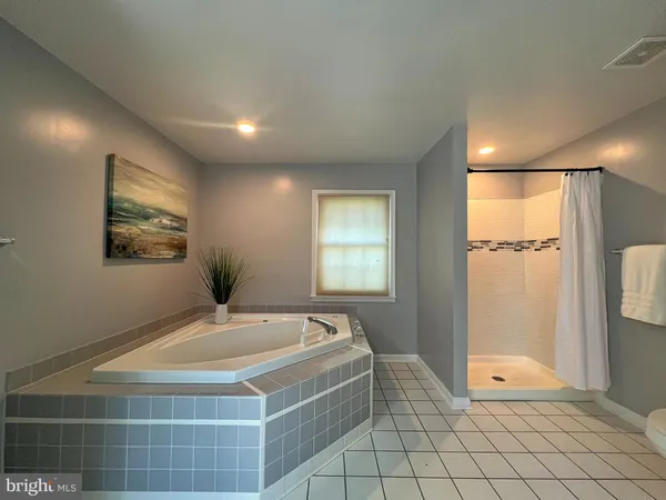 a spacious bathroom with a granite countertop sink a mirror and a bathtub