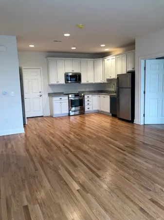 a view of kitchen with kitchen island granite countertop wooden floors and stainless steel appliances