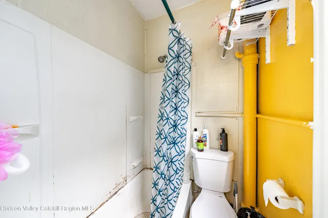 a bathroom with a toilet and a shower curtain