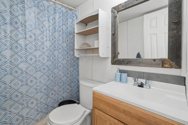 a bathroom with a granite countertop toilet sink and mirror