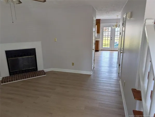 a view of an empty room with wooden floor and a fireplace