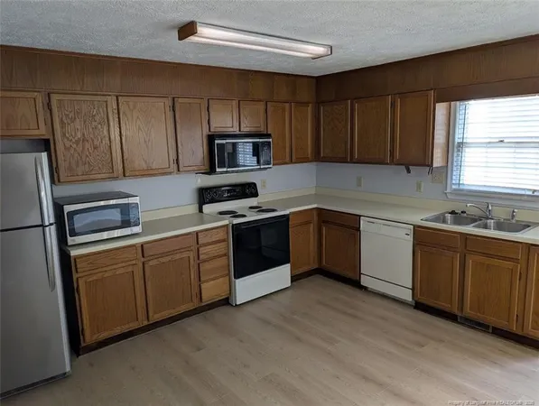 a kitchen with stainless steel appliances granite countertop a sink a stove a refrigerator with grey cabinets and wooden floor