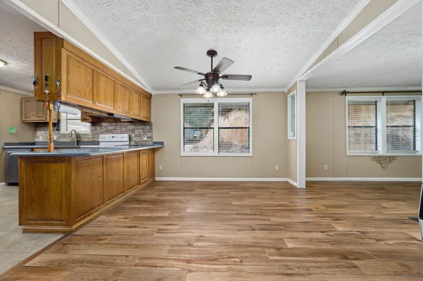 a kitchen with stainless steel appliances granite countertop a refrigerator a oven and a sink with wooden cabinets